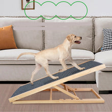 Labrador puppy walking up an adjustable wooden dog ramp with a black non-slip surface beside a sofa