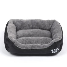 Black and grey plush dog bed with raised cushioned sides, a soft padded base and white paw print detail