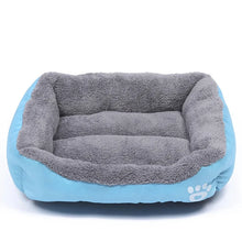 Blue and grey plush dog bed with raised cushioned sides, a soft padded base and white paw print detail