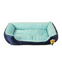Blue cushioned dog bed with yellow polka dots, raised padded sides, a soft base and a small flower detail