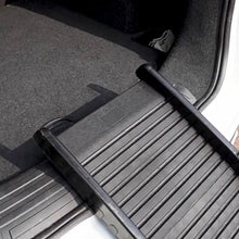 Close-up of a black foldable dog ramp with a ridged non-slip surface attached to a car boot