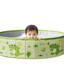 Green round foldable kids pool with crocodile print, filled with water and shown with a young child