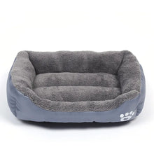 Grey plush dog bed with raised cushioned sides, a soft padded base and white paw print detail
