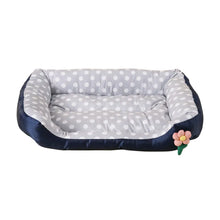 Grey polka dot cushioned dog bed with raised padded sides, a soft base and a small flower detail