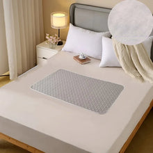 Grey quilted waterproof bed protector pad with textured surface and rounded edges placed on a mattress