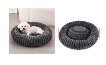 Small white dog resting in a dark grey ribbed donut dog bed with raised cushioned sides and a padded centre