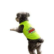 Small curly-haired dog wearing a neon green soccer-themed shirt with a GOAL graphic while standing on its hind legs