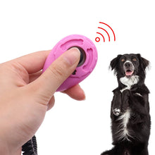 hand holding pet clicker with a dog on the background