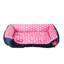 Pink polka dot cushioned dog bed with raised padded sides, a soft base and a small flower detail