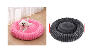 Small white dog resting in a pink ribbed donut dog bed beside a grey version with raised cushioned sides and a padded centre
