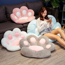 Plush paw-shaped floor chairs in pink, white, grey and light blue, shown in a living room seating setup